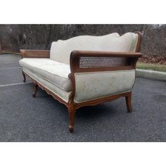 an old couch sitting in the middle of a parking lot with no one around it