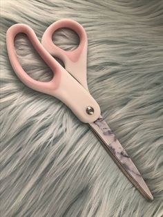 a pair of pink scissors sitting on top of a fur covered surface with the handles extended