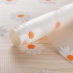 a roll of clear plastic sitting on top of a wooden table next to a flowery wallpaper