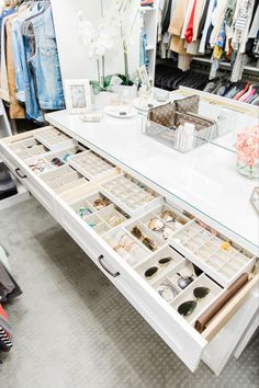 a white dressing table with drawers filled with shoes and other items on display in a clothing store