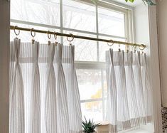 a window with white curtains and a potted plant