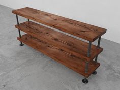 two wooden shelves sitting on top of each other in a cement floored room next to a wall