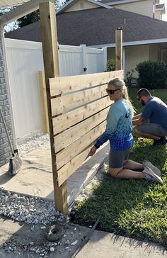 two people working on a wooden fence in the yard