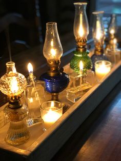 candles are lit on a tray with glass vases