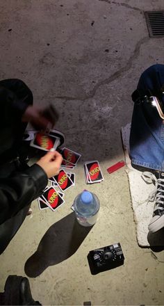 a person sitting on the ground next to some stickers and a bottle of water