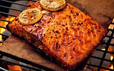 a piece of meat cooking on top of a bbq grill with lemon slices and onions