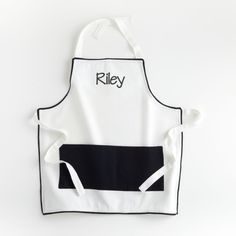 an apron with the word riley printed on it, hanging from a white wall behind