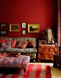 a living room filled with furniture and paintings on the wall above it's red walls