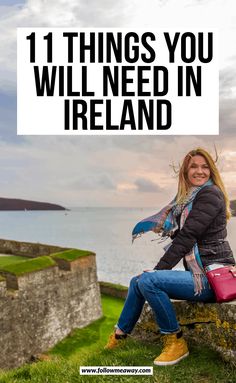 a woman sitting on top of a stone wall next to the ocean with text overlay that reads 11 things you will need in ireland