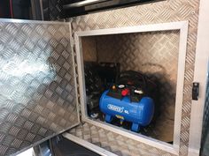 a blue and black air compressor in a metal box