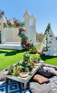 an outdoor party setup with balloons and decorations on the grass, including a white castle