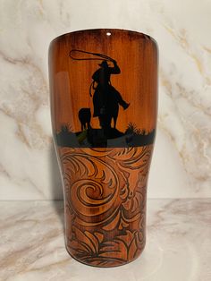 an image of a cowboy on horseback with his lasso in hand engraved on a wooden cup