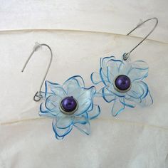 pair of earrings with flower design on white cloth background and blue glass bead earwires