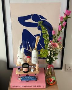 a vase with flowers and candles on top of a table next to a pink book