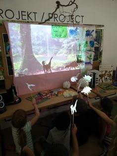 children are playing with an interactive screen in the classroom