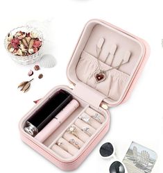 an open pink case with jewelry and sunglasses on the table next to it, along with other items