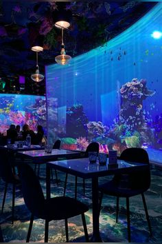 people are sitting at tables in front of a large aquarium wall with fish and corals