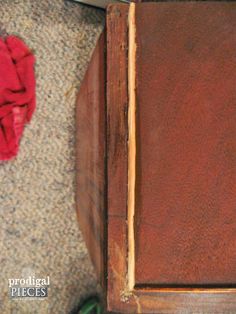 an old wooden table with a red cloth on the floor and a pair of green shoes next to it