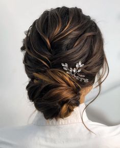 a woman with her hair in a low bun, wearing a white shirt and a gold leaf comb