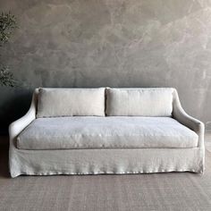 a white couch sitting in front of a wall with a potted plant on it