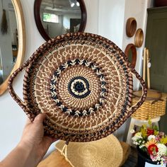 a person holding up a woven basket in front of a wall with mirrors on it