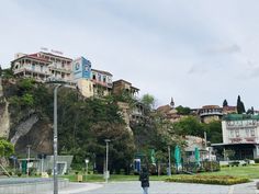 a man is walking down the street in front of some buildings on top of a hill