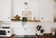 a stove top oven sitting inside of a kitchen next to white cupboards and wooden counter tops