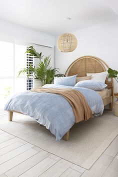 a bedroom with white walls and flooring has a wicker headboard on the bed