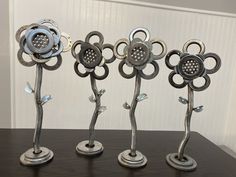 four metal flower sculptures sitting on top of a table