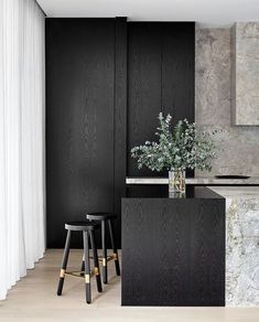 two stools sit in front of a black kitchen island with marble countertops and walls