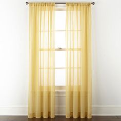 a yellow curtain hanging on the side of a white wall next to a wooden floor