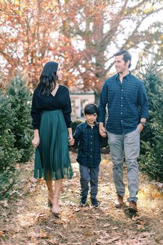 a man and woman holding hands while walking with a young boy in front of them