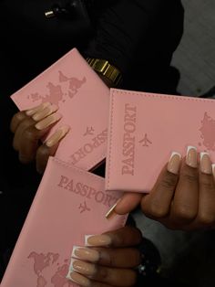 a person holding two pink passport cases with white nails on them and one has gold accents