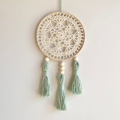 a white doily with tassels hanging on a wall next to a string