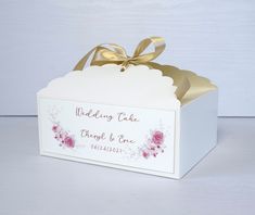 a wedding cake box with a gold ribbon