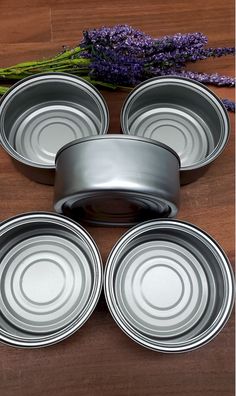 four tin pans sitting on top of a wooden table next to lavender sprigs