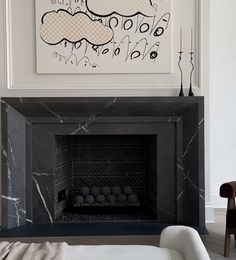 a black and white fireplace in a living room next to a painting on the wall