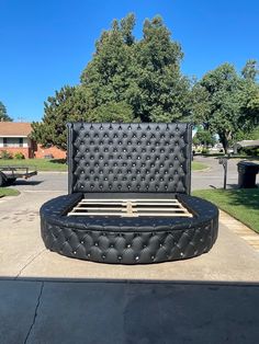 a black bed sitting in the middle of a parking lot next to a park bench