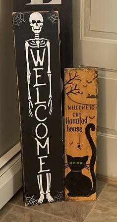 two halloween signs sitting next to each other on the floor in front of a door