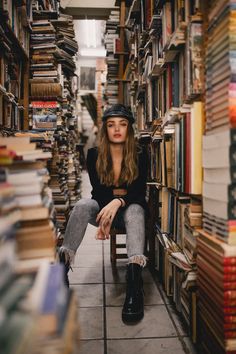 a woman sitting on a chair in front of a book shelf filled with lots of books