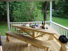 a picnic table on a deck with bottles of wine