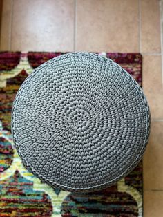 a round ottoman sitting on top of a rug