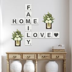 a table with vases and flowers on it in front of a wall that says fab, home, i love you