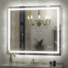 a bathroom vanity with a large lighted mirror above it and a vase on the counter