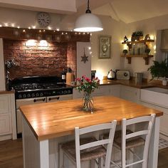 a kitchen with wooden counter tops and white chairs next to an island in front of a stove top oven