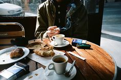 a man sitting at a table with coffee and pastries