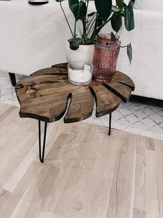 a wooden table with two planters on it in front of a couch and coffee table