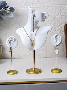 three white mannequins with necklaces and earring stands on a counter