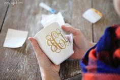 a person holding a coffee mug with the word monogram on it, sitting at a wooden table