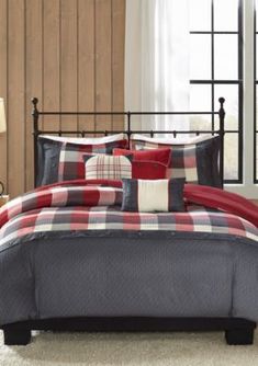 a bed in a room with a plaid comforter and pillows on top of it